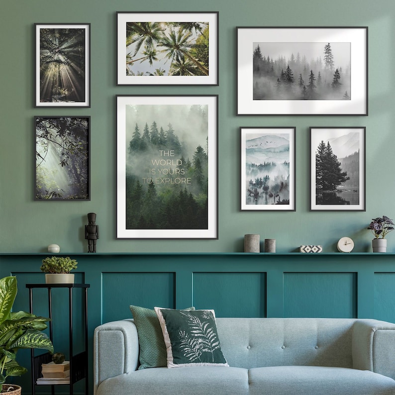 May include: A living room interior with a teal green wall and a light blue sofa. The wall is decorated with framed prints of forest scenes. The prints feature a variety of trees, including palm trees, pine trees, and ferns. The prints are arranged in a symmetrical pattern on the wall. The text "The world is yours to explore" is printed on one of the prints.