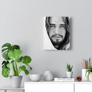 May include: Black and white portrait of a man with long hair and a beard. He is wearing a white robe and looking directly at the viewer. The image is printed on canvas.