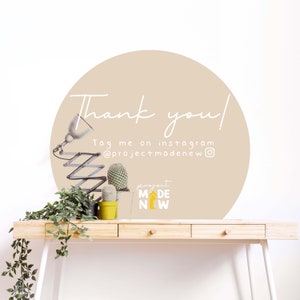 Może przedstawiać: Beżowe koło z tekstem "Thank you!" i "Tag me on instagram @projectmadenew" na białej ścianie. Na pierwszym planie znajdują się dwie małe doniczki z kaktusami i lampa na drewnianym biurku.