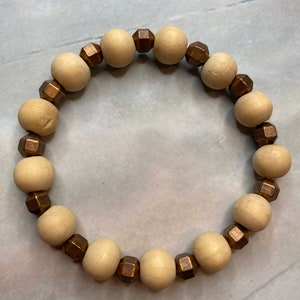 May include: A wooden bead bracelet with brown metal accents. The bracelet is made of natural wood beads and has a simple, elegant design.