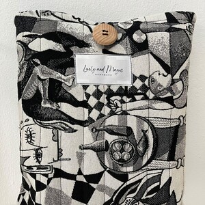 May include: Black and white patterned cushion cover with a wooden button and a label that reads "Lovely and Magic Handmade".