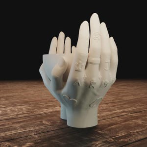 May include: A white ceramic hand-shaped planter with detailed tattoos and a ring. The planter is designed to hold small plants or decorative items. The fingers are slightly curved, creating a unique and artistic display piece.
