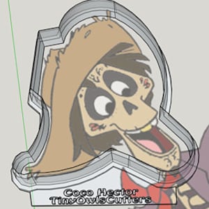 Puede incluir: Un cortador de galletas con forma de Héctor de la película Coco. El cortador está hecho de plástico transparente y presenta un diseño detallado de la cara de Héctor, incluyendo su sombrero, bigote y rasgos de esqueleto. El texto "Coco Hector TinyOwlCutters" está impreso en el cortador.
