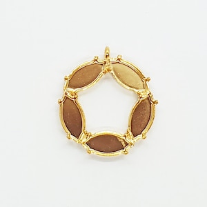 May include: Gold-toned metal pendant with a circular design featuring six oval-shaped cutouts. The pendant has a loop at the top for attaching a chain.