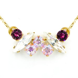 May include: A gold chain necklace with a cluster of clear and pink iridescent crystals and two small purple crystals.