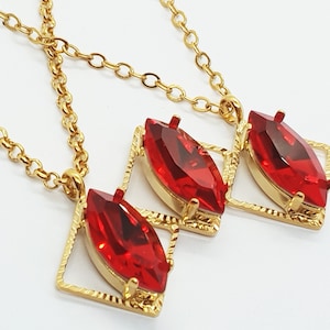May include: Three gold necklaces with red gemstone pendants. Each pendant is a marquise-shaped stone set in a gold frame.