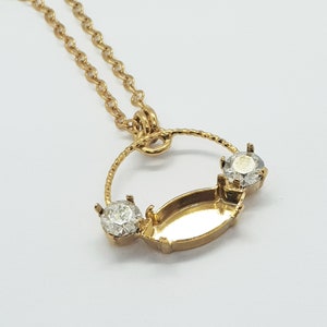 May include: Gold pendant necklace with a circular design and two clear rhinestones. The pendant has a large oval-shaped setting in the center.