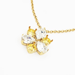 May include: A gold chain necklace with a flower-shaped pendant featuring five clear crystal stones.