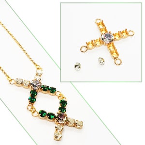 May include: A gold necklace with a pendant featuring a double-circle design with green and clear rhinestones.