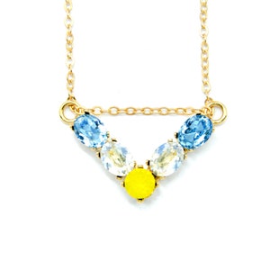 May include: A gold chain necklace with a V-shaped pendant featuring blue, white, and yellow oval-shaped rhinestones.