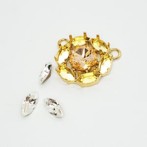 May include: Gold-toned metal setting with a clear, light peach-colored gemstone in the center. Three smaller clear gemstones are also included.