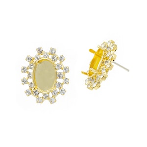 May include: A pair of gold-tone earring settings with a clear rhinestone halo around an oval-shaped bezel. The bezels are empty and ready to be filled with a stone or other embellishment.