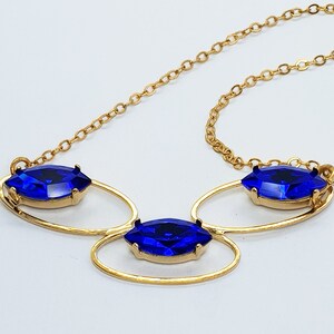 May include: A gold necklace with three blue marquise-shaped stones set in a delicate, openwork design.