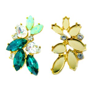 Puede incluir: Dos engastes de pendientes de metal dorado con diseño floral. Un engaste está lleno de piedras de cristal verdes, blancas y verde claro. El otro engaste está vacío.