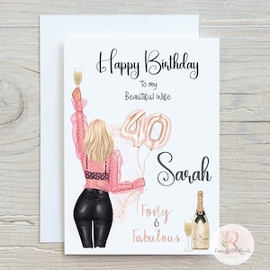 May include: A birthday card with a pink and gold illustration of a woman holding a glass of champagne and balloons that say "40". The text on the card reads "Happy Birthday to my Beautiful Wife Sarah Forty & Fabulous".