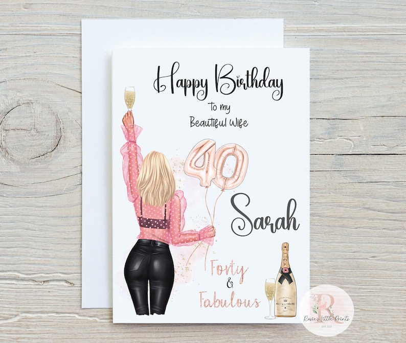 May include: A birthday card with a pink and gold illustration of a woman holding a glass of champagne and balloons that say "40". The text on the card reads "Happy Birthday to my Beautiful Wife Sarah Forty & Fabulous".