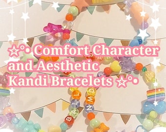 May include: Colorful kandi bracelets with beads, charms, and letters spelling "BAL" and "MIND". The bracelets are on a pink and white background with stars.