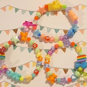 Pu&ograve; includere: Tre braccialetti colorati con perline e ciondoli arcobaleno, stelle e cuori. I braccialetti compongono le parole "BALLOON", "PARTY" e "NUMBERS".