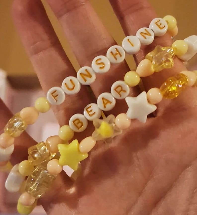 Pu&ograve; includere: Tre braccialetti di perline con perline gialle e bianche e ciondoli a forma di stella. I braccialetti compongono le parole "FUNSHINE", "BEAR" e "INE".