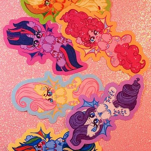 May include: A collection of five die-cut stickers featuring stylized pony characters with bat-like wings. The characters are depicted in vibrant colors including yellow, purple, pink, light blue, and dark blue, each with unique hair and cutie mark designs.