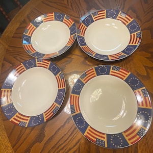 May include: Set of four white ceramic soup bowls with a red, white, and blue American flag design. The bowls have a blue rim and a gold star pattern.