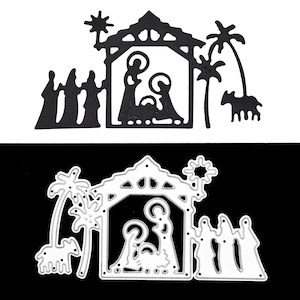 May include: Two die-cut metal Christmas nativity scene designs. One is black, the other is silver. Each features a stable with Mary, Joseph, and baby Jesus, along with the three wise men, palm trees, and a donkey.