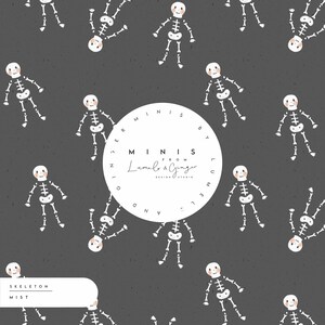 May include: A seamless pattern featuring white skeletons with orange faces on a dark grey background. The pattern includes the text "MINIS FROM Lumelo & Ginger DESIGN STUDIO" in a white circle.