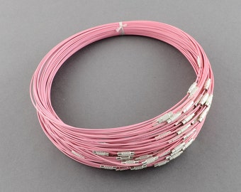 May include: A close-up of a bundle of pink elastic cord necklaces with silver clasps. The necklaces are coiled together in a circle.