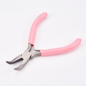May include: Pink handled pliers with a silver metal head. The pliers have a curved shape and are designed for jewelry making.
