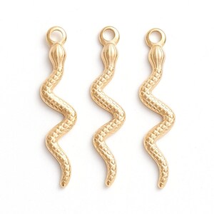 May include: Three gold snake charms with a textured surface. The charms are approximately 5 cm long and have a loop at the top for attaching to jewellery.