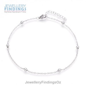 May include: A silver anklet with a delicate chain and five small round beads.