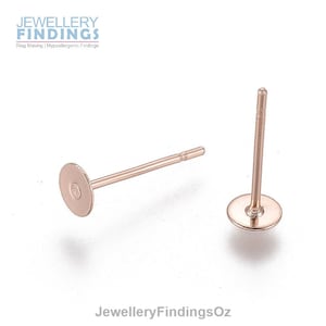 May include: Two rose gold earring posts with flat round backs. The posts are about 1 inch long.