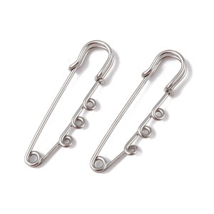 May include: Two silver safety pins with three decorative loops on each pin.
