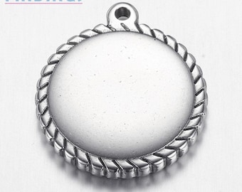 May include: Silver-toned metal pendant with a round, smooth surface and a rope-like border. The pendant has a small loop at the top for attaching a chain or cord.