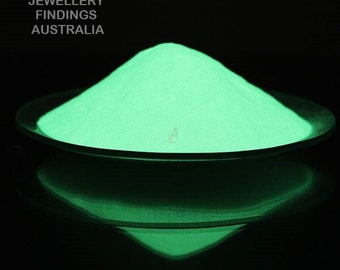 May include: A pile of bright green glow-in-the-dark powder in a black dish. The powder is glowing brightly in the dark.