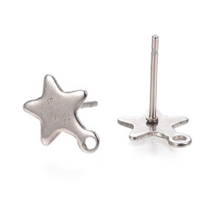 May include: A pair of silver star-shaped earring findings with a jump ring. The earrings are made of metal and have a post back.