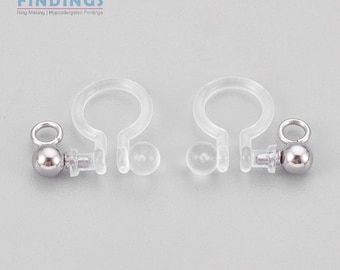 May include: Two clear plastic earring backs with silver ball ends. The earring backs are designed to be used with post earrings.