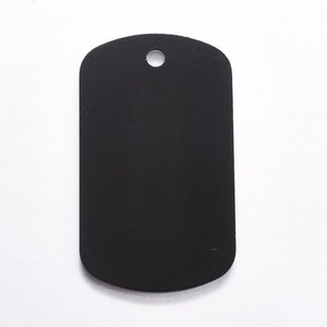 May include: A black metal dog tag with a round hole at the top.