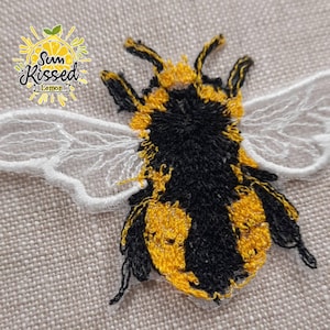 May include: Embroidered bumble bee patch with yellow and black stripes and white wings. The patch has a white background with the text "Sun Kissed Lemon" in a yellow circle with a lemon slice.