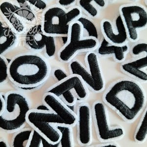 May include: A selection of black embroidered letters with a white trim. The letters are in different fonts and sizes, including the letters "O", "N", "U", "P", and "D". These patches are suitable for customising clothing or accessories.