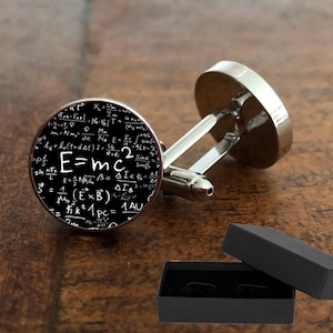 May include: Silver cufflinks with a black circular design featuring the famous equation "E=mc²" surrounded by other scientific formulas and symbols.