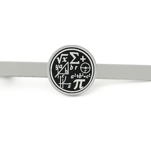 May include: Silver-toned tie clip with a circular black and white emblem featuring mathematical symbols. The clip is rectangular and has a polished finish. The emblem includes symbols like the square root, pi, and the Pythagorean theorem.