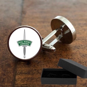 May include: Silver cufflinks with a round, white background featuring a green and white Royal Marines Commando emblem. The cufflinks come in a black gift box.