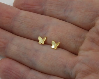 May include: A pair of gold butterfly stud earrings. The earrings are small and delicate, and they are perfect for everyday wear.