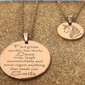 May include: Two rose gold necklaces with round pendants. One pendant has an engraved quote: "Forgive quickly, kiss slowly, Love truly, laugh uncontrollably and never regret anything that made you Smile". The other pendant has a line drawing of a unicorn with the word "Emma" engraved below.