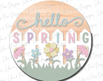 Könnte beinhalten: Ein rundes Holzschild mit den Worten "hello spring" in einem Design aus weißem Lattenzaun. Der Zaun ist mit pastellfarbenen rosa, gelben und blauen Blumen verziert. Das Schild ist perfekt für ein Frühlings-Dekoprojekt.