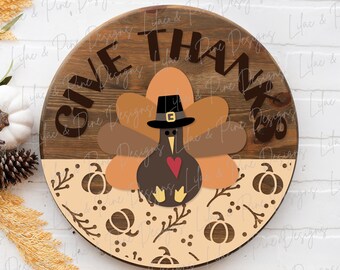 May include: A round wooden sign with the text "Give Thanks" in brown lettering. The sign is decorated with a brown turkey wearing a pilgrim hat and a red heart. The bottom half of the sign is decorated with a tan background with brown leaves, pumpkins, and berries.