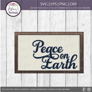 May include: A wood-framed sign with a white background and the text "Peace on Earth" in a dark blue cursive font.