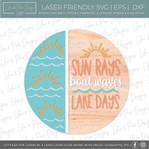 Op de afbeelding: Een rond houten bord met een blauw en wit golfpatroon aan de linkerkant en de tekst "SUN RAYS boat waves LAKE DAYS" in oranje en wit aan de rechterkant.