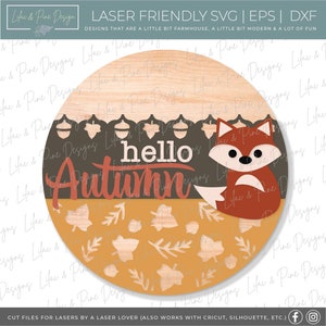 May include: A round wooden sign with a fox and the text "hello autumn" in red and orange. The background is a dark brown with a pattern of acorns and a light brown with a pattern of leaves.